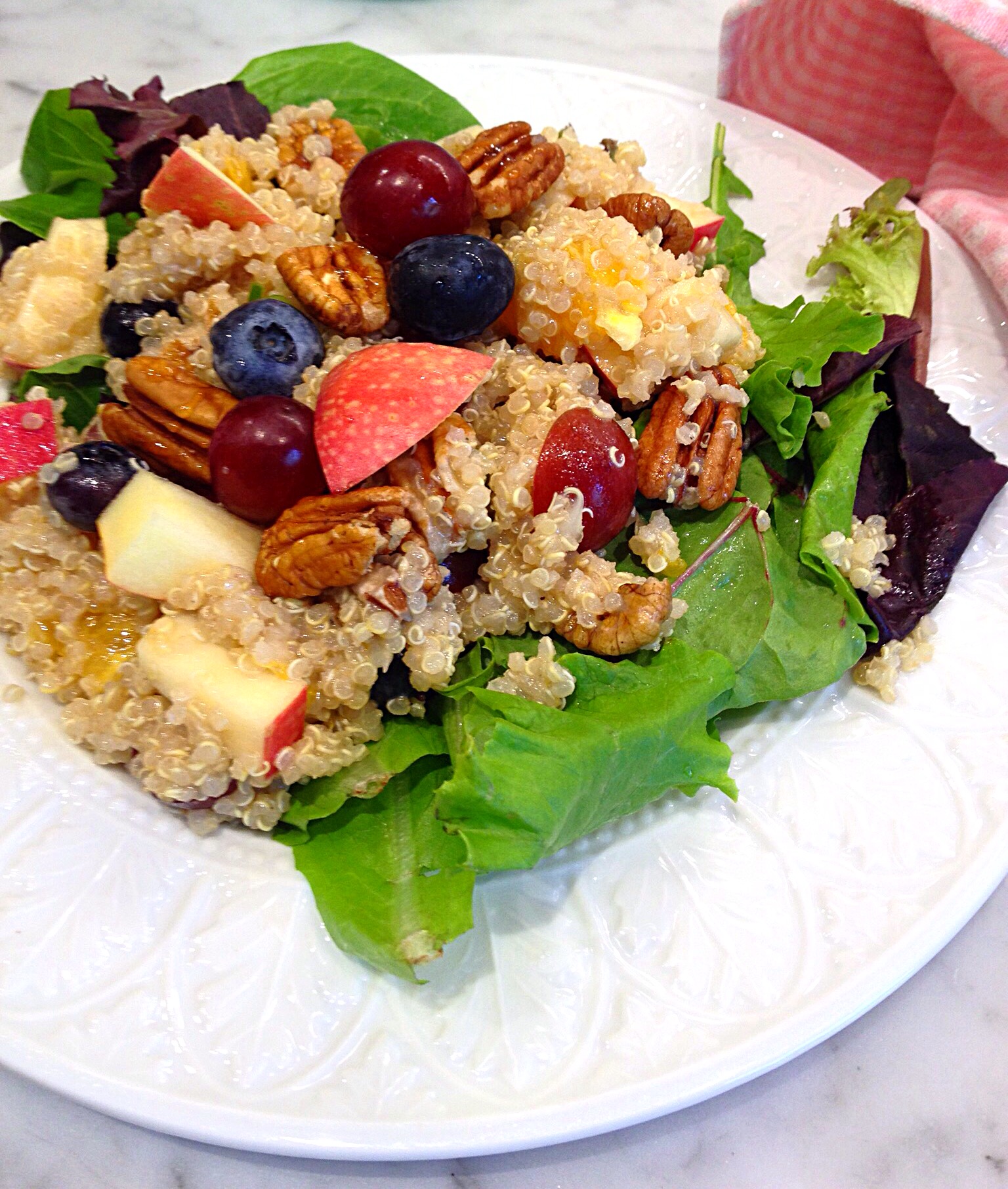 Quinoa Salad with Fruit and Nuts served on a bed of salad greens