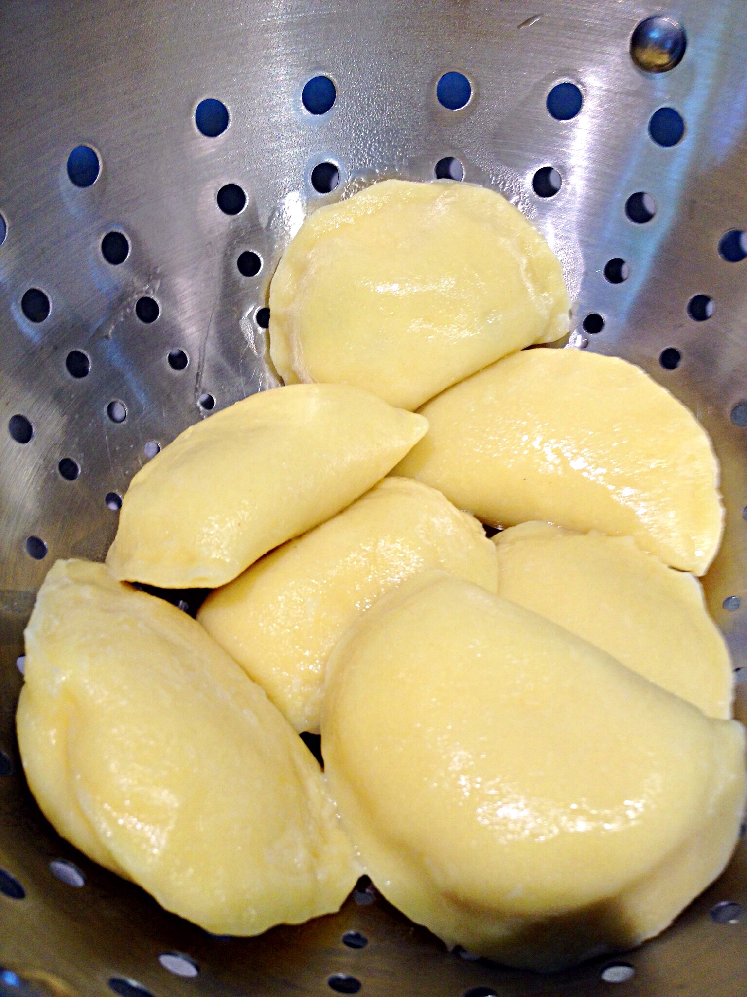 Photo showing boiled pierogi draining in a colander