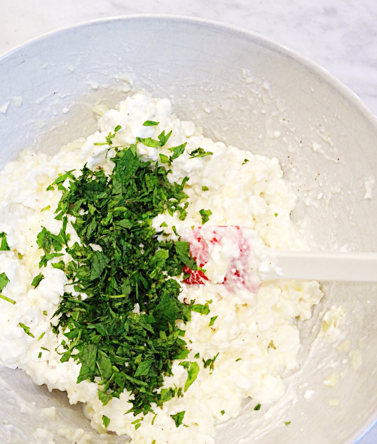 Photo showing the adding of mint, and salt and pepper to the filling.
