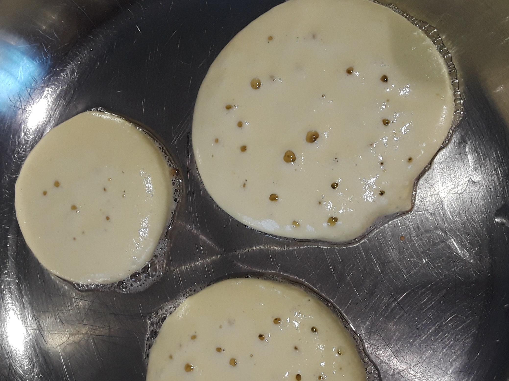 Pancakes frying on one side with small air bubbles forming on surface