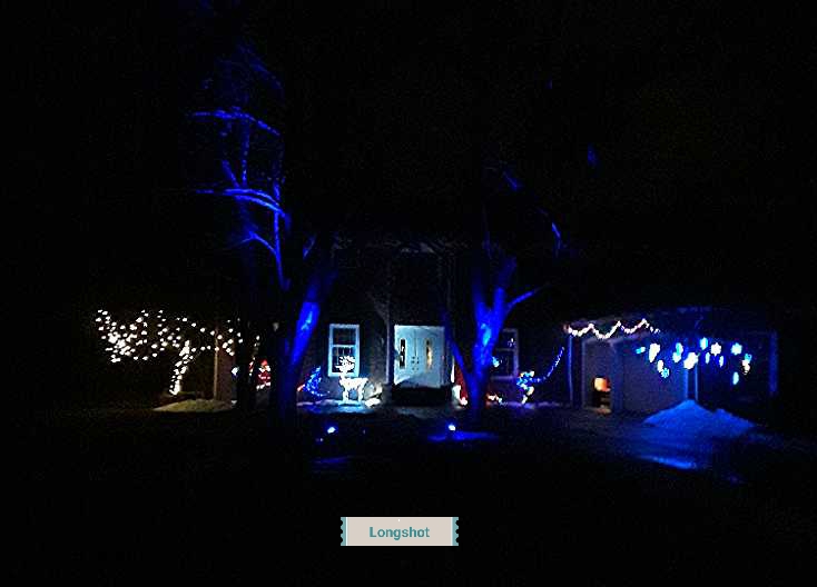 long view of home illuminated by colored lights and blue floodlights