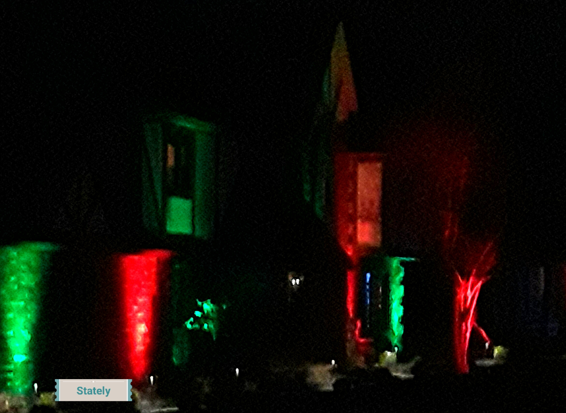 red and green floodlights illuminate the stucco of a Tudor style home