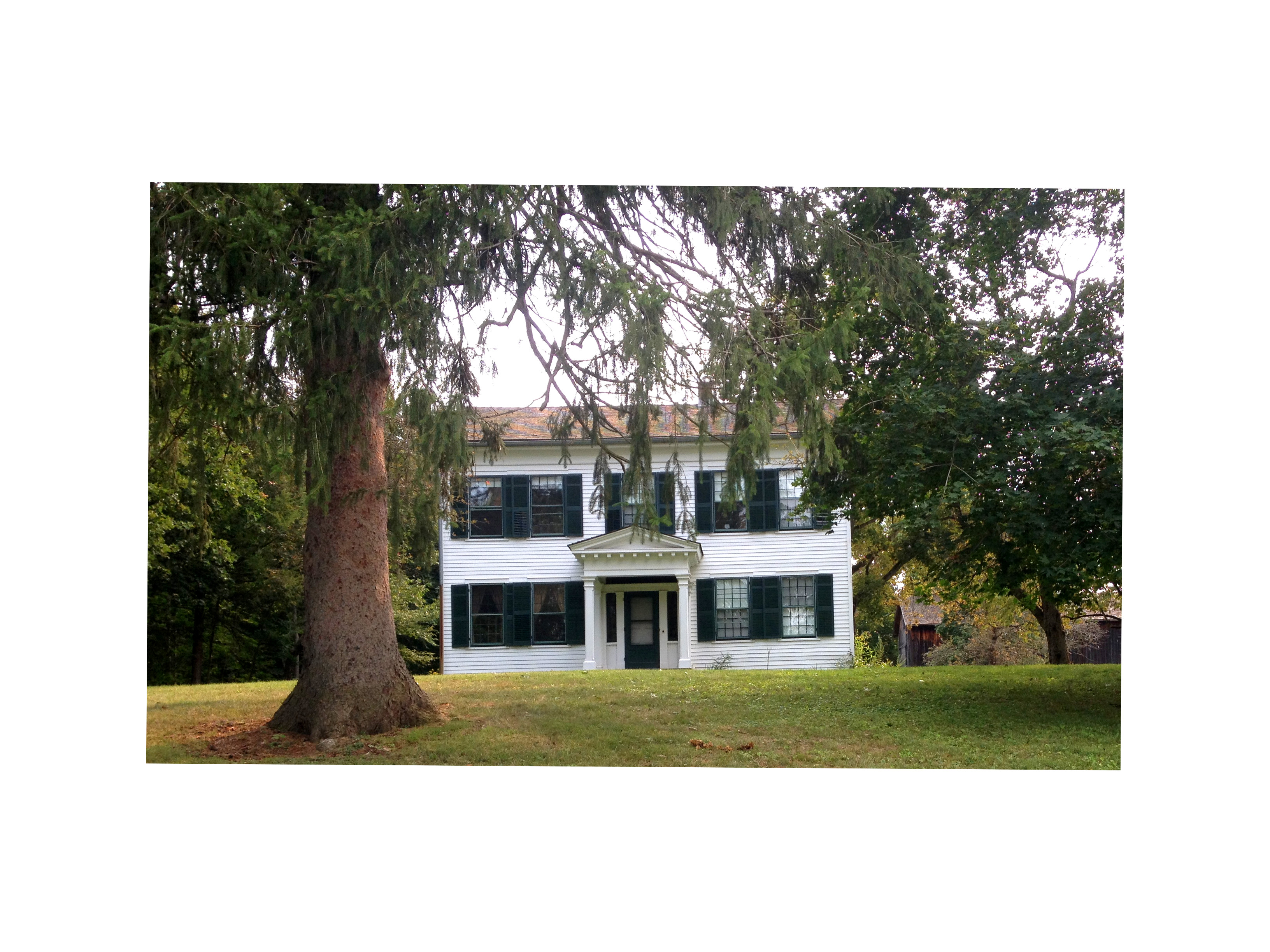 white clapboard farmhouse with dark green shutters