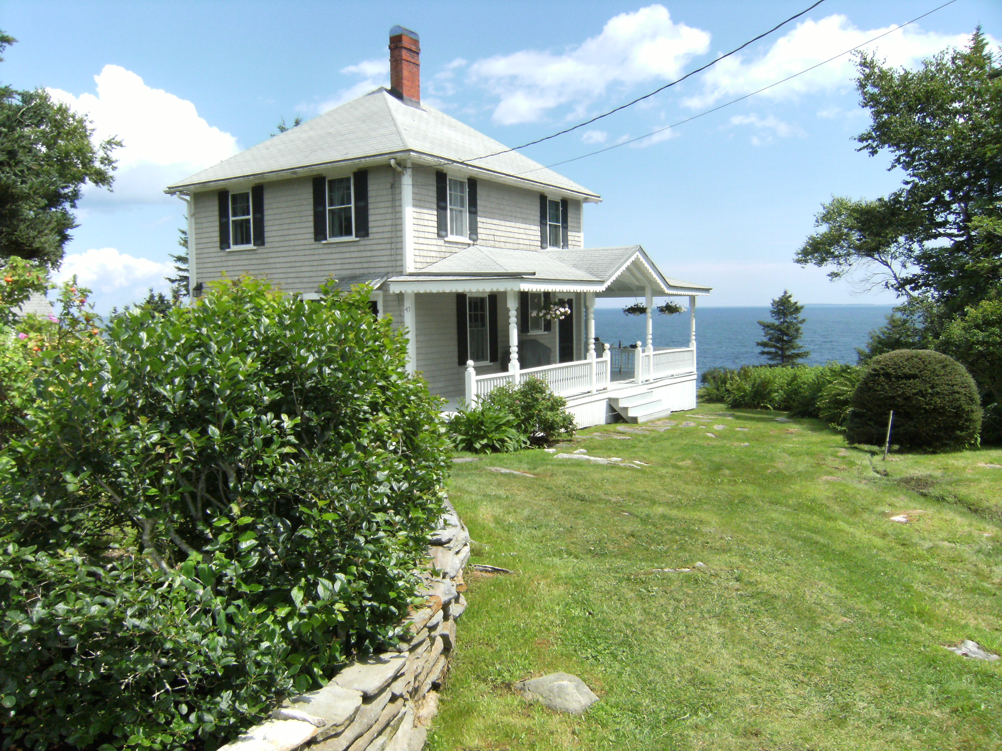 Gray frame cottage with wrap around porch overlooking the Atlantic Ocean.