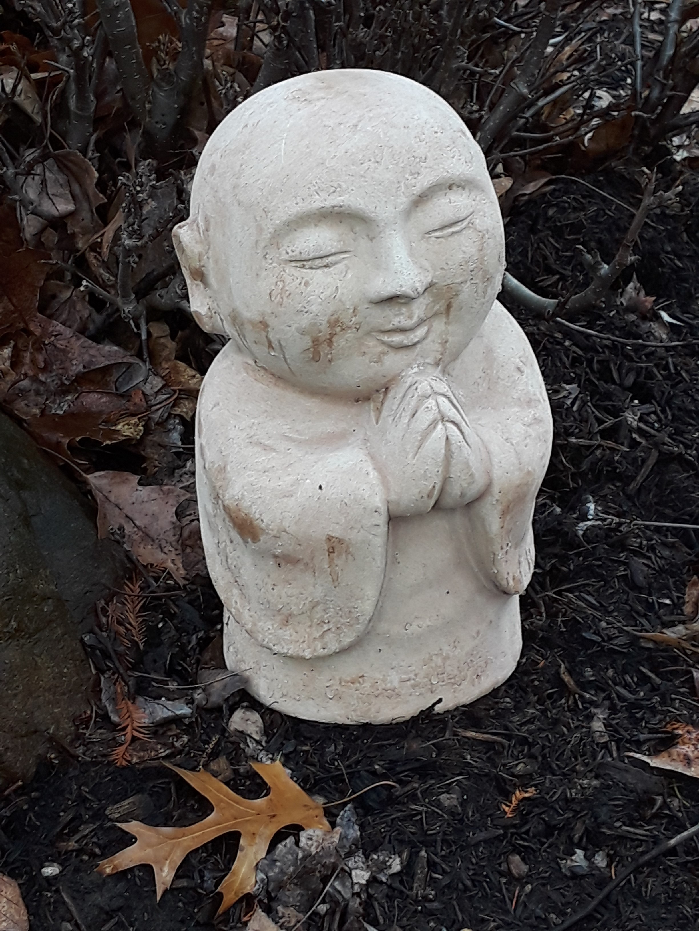 concrete garden Buddha with hands folded in prayer