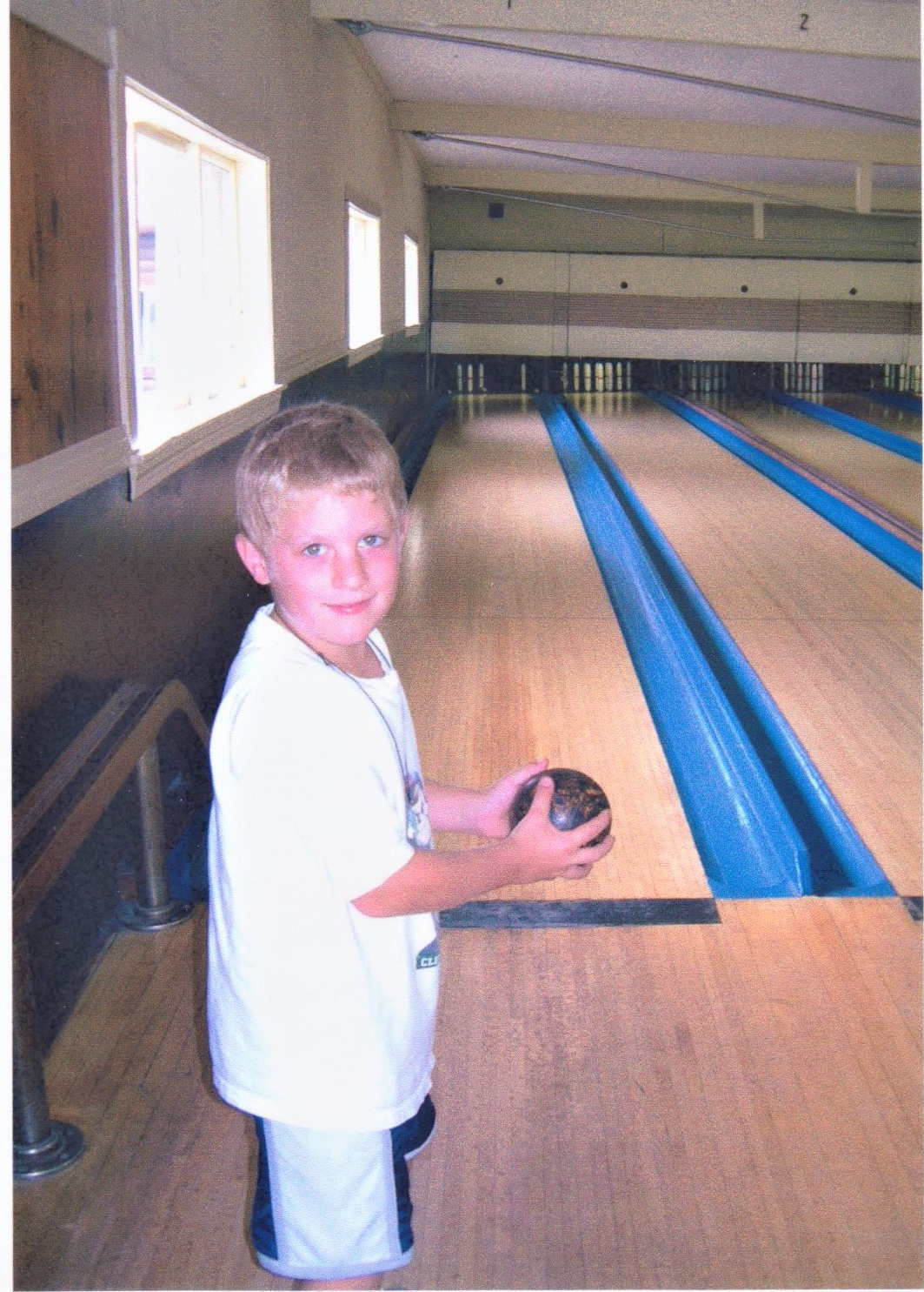 Young boy getting ready to roll his bowling ball down the alley at duckpin bowling.