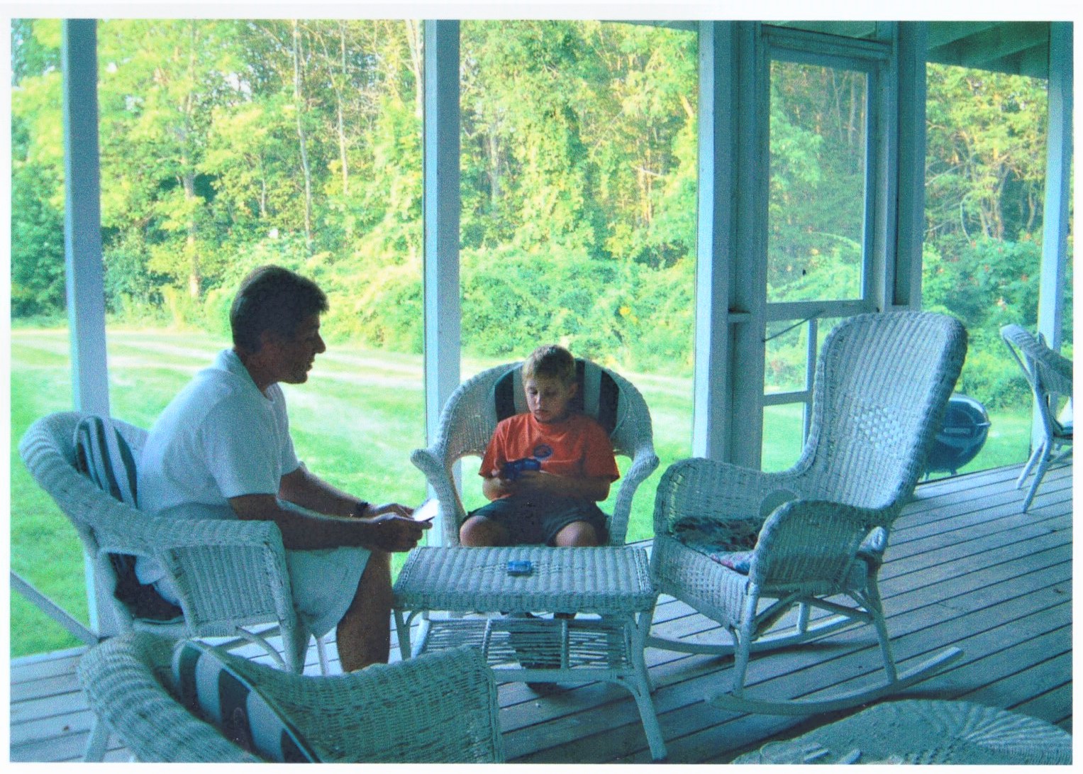 Father and son relax on wicker furniture in the hotel's screened back porch.
