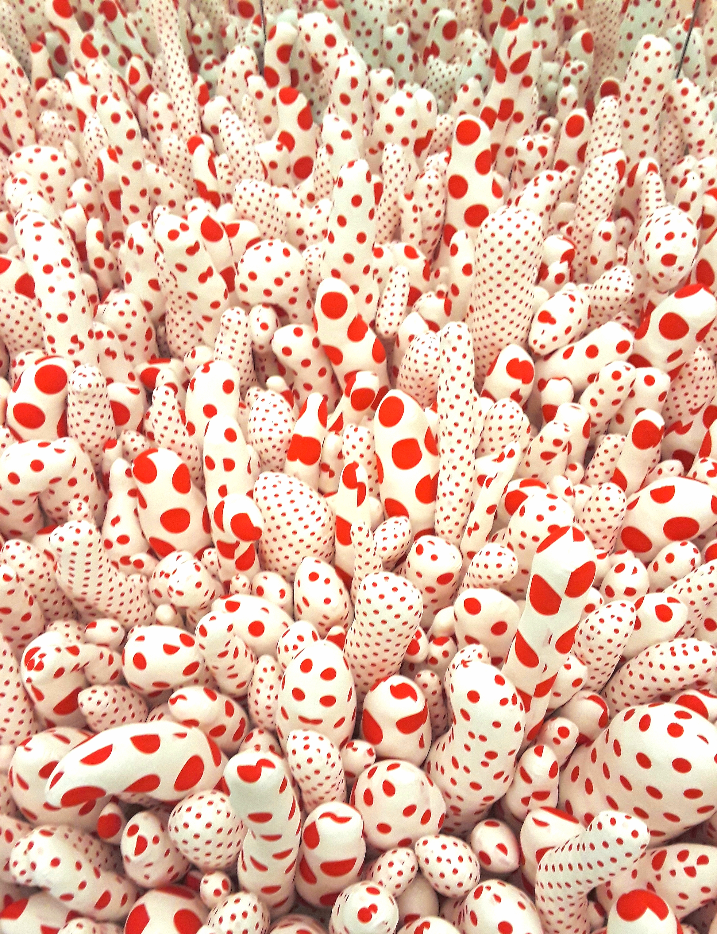 scores of sewn and stuffed white fabric phallus-shaped sculptures dotted in red