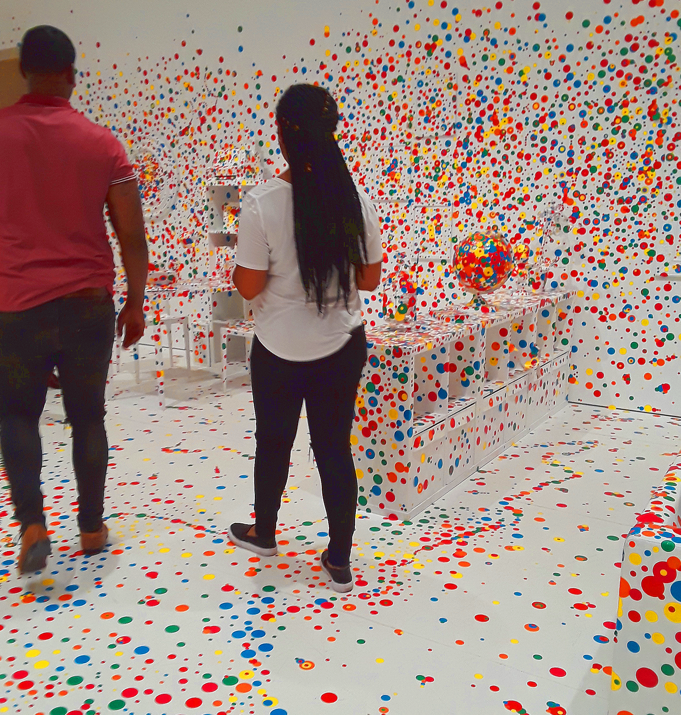 a couple walks through the all white room decorated with dot stickers