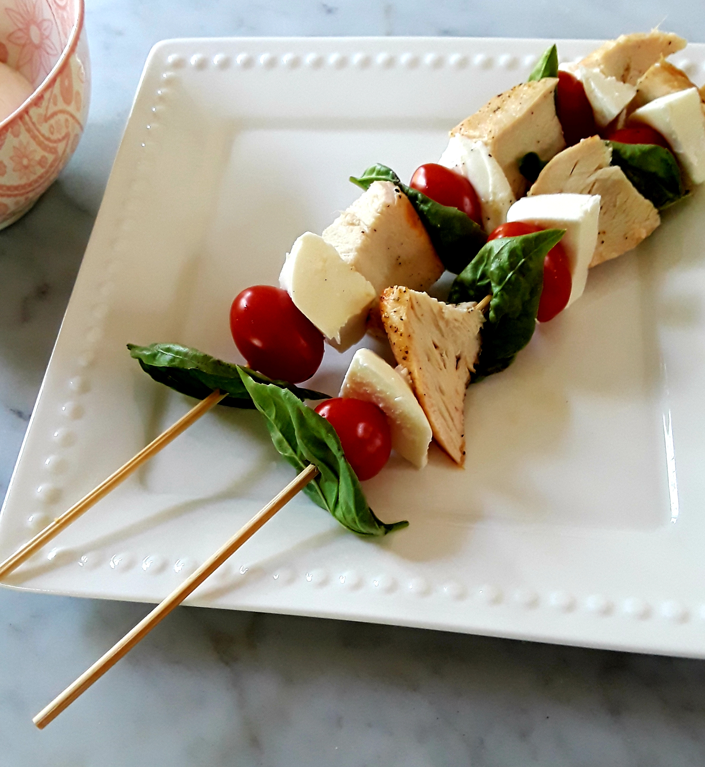 basil leaves, tomato, fresh mozzarella and chicken cubes on a stick