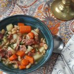 Ham and bean soup with chicken broth, carrots, potatoes, white beans, and arugula.