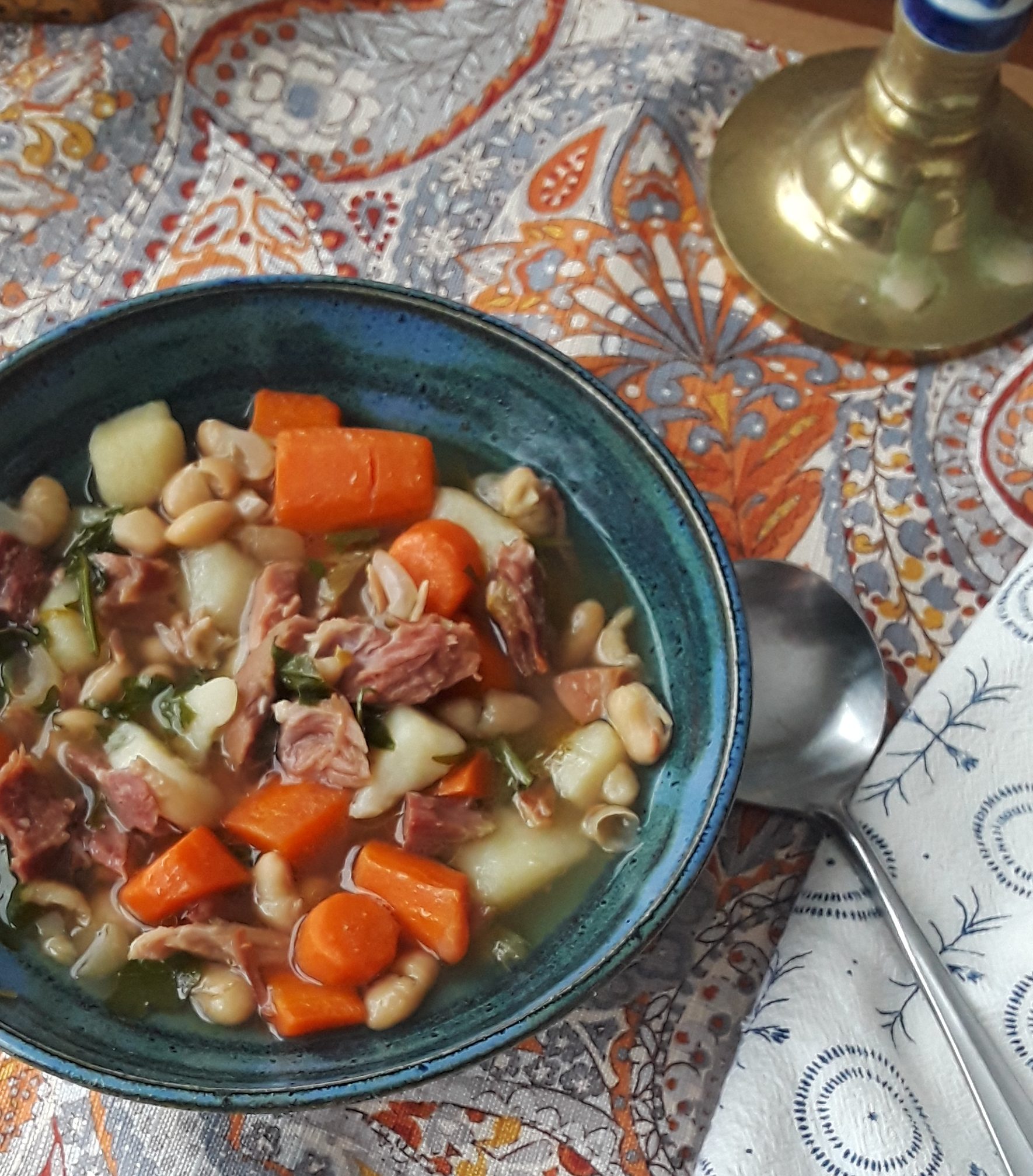 Ham and bean soup with chicken broth, carrots, potatoes, white beans, and arugula.