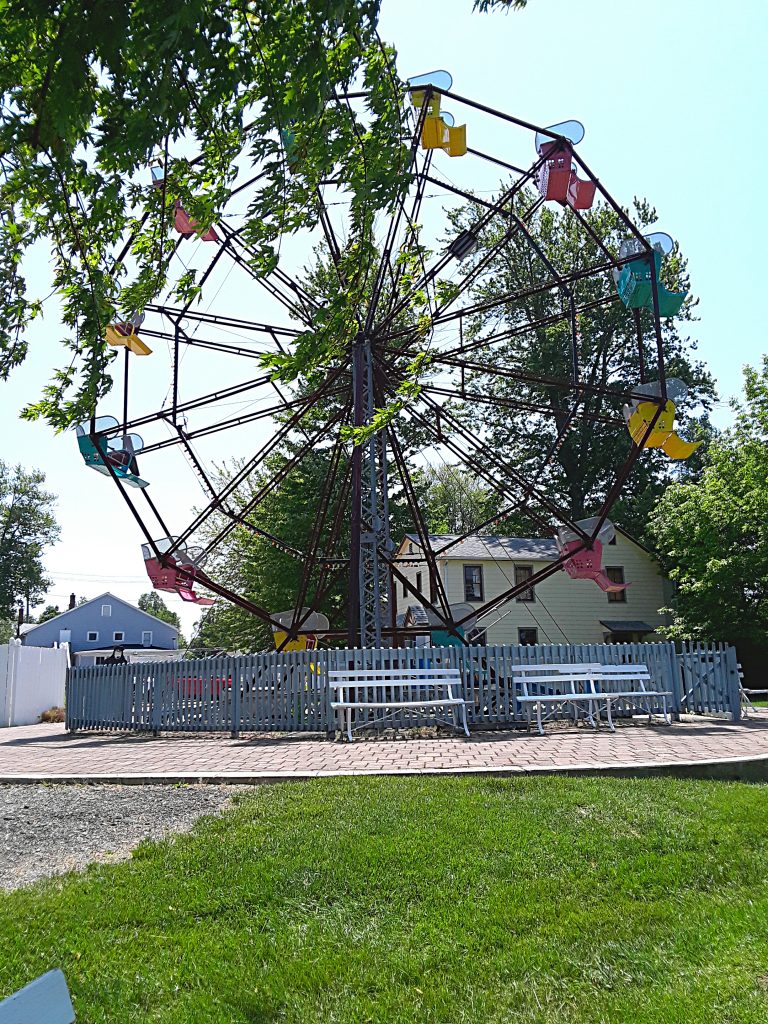A Ferris Wheel with yellow, red, and blue cars.