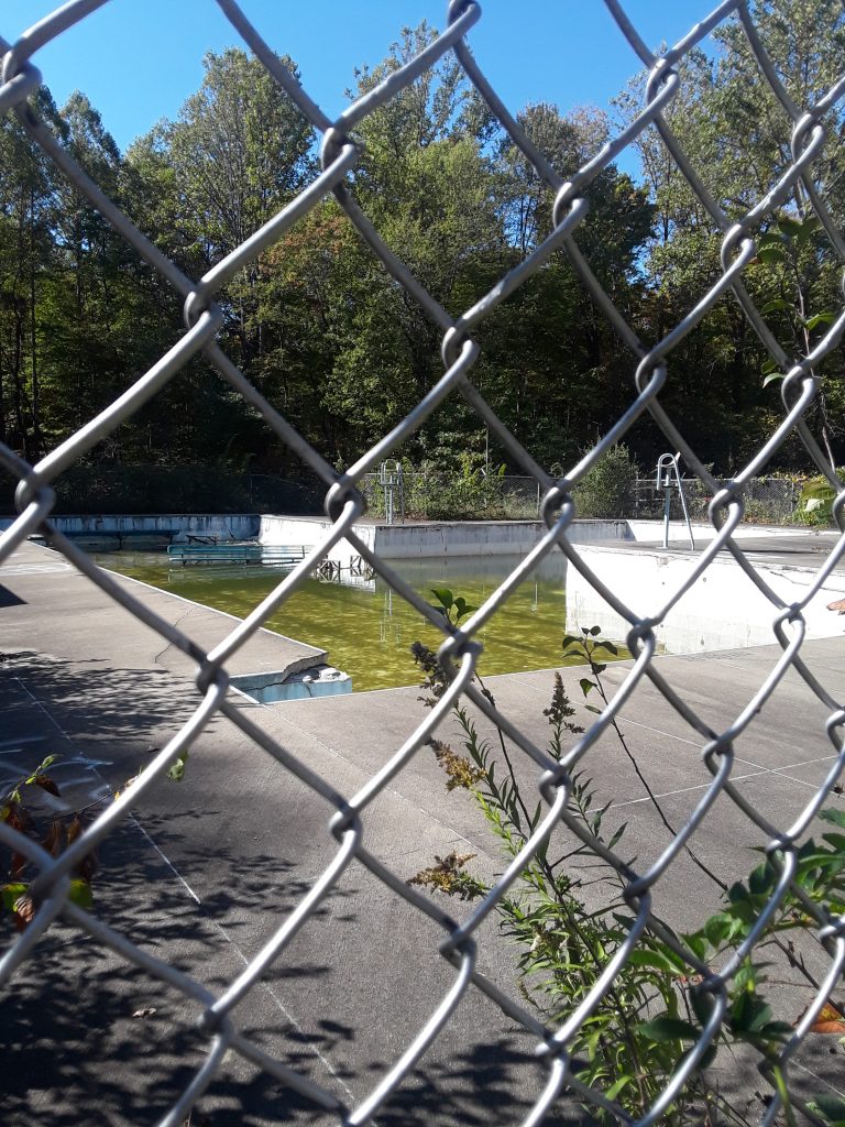 old swimming pool viewed through chain link fence