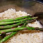 asparagus spears are spread out on top of cooked rice in the rice pot