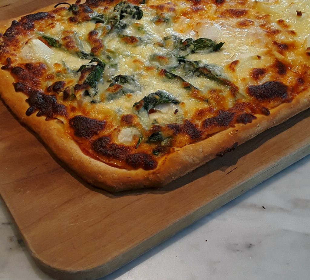 Baked homemade pizza with spinach and cheese toppings