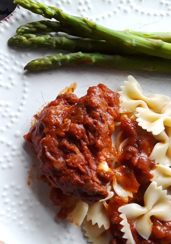 Greek chicken is served with fresh asparagus spears and bow-tie noodles