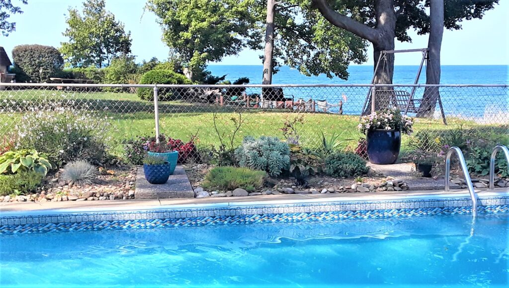 The inground pool is flanked by gardens.