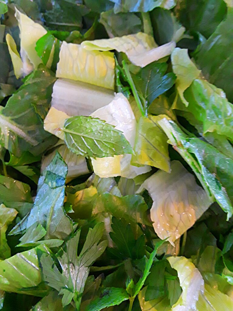 romaine lettuce is chopped and mixed with parsley and mint leaves.