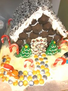 A gingerbread house is trimmed with snow caps, kisses, and candy canes