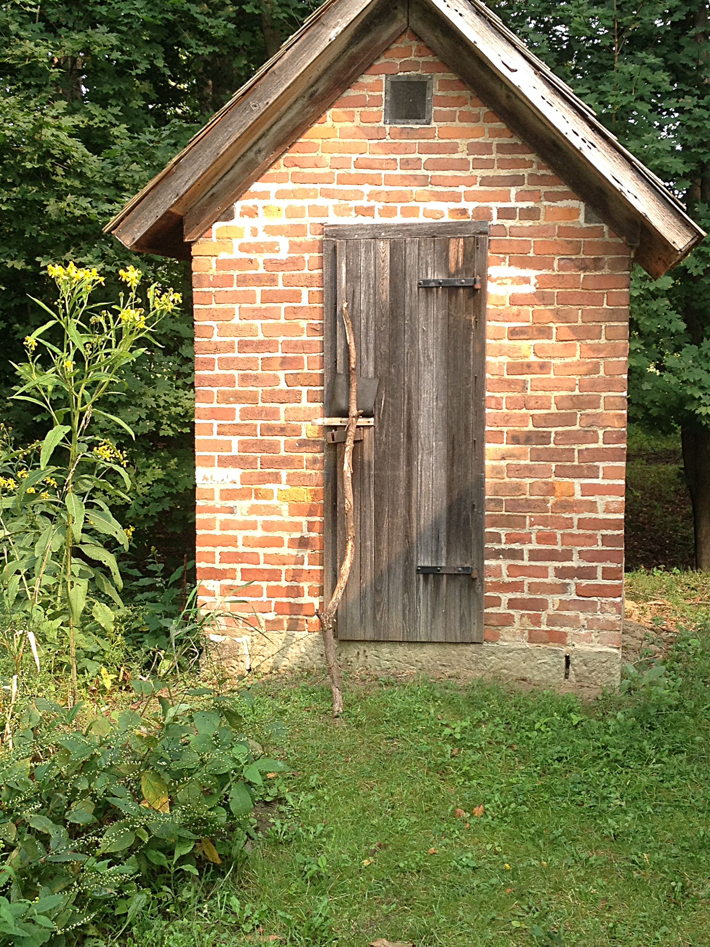 small brick outbuilding behind historic white clapboard farmhouse