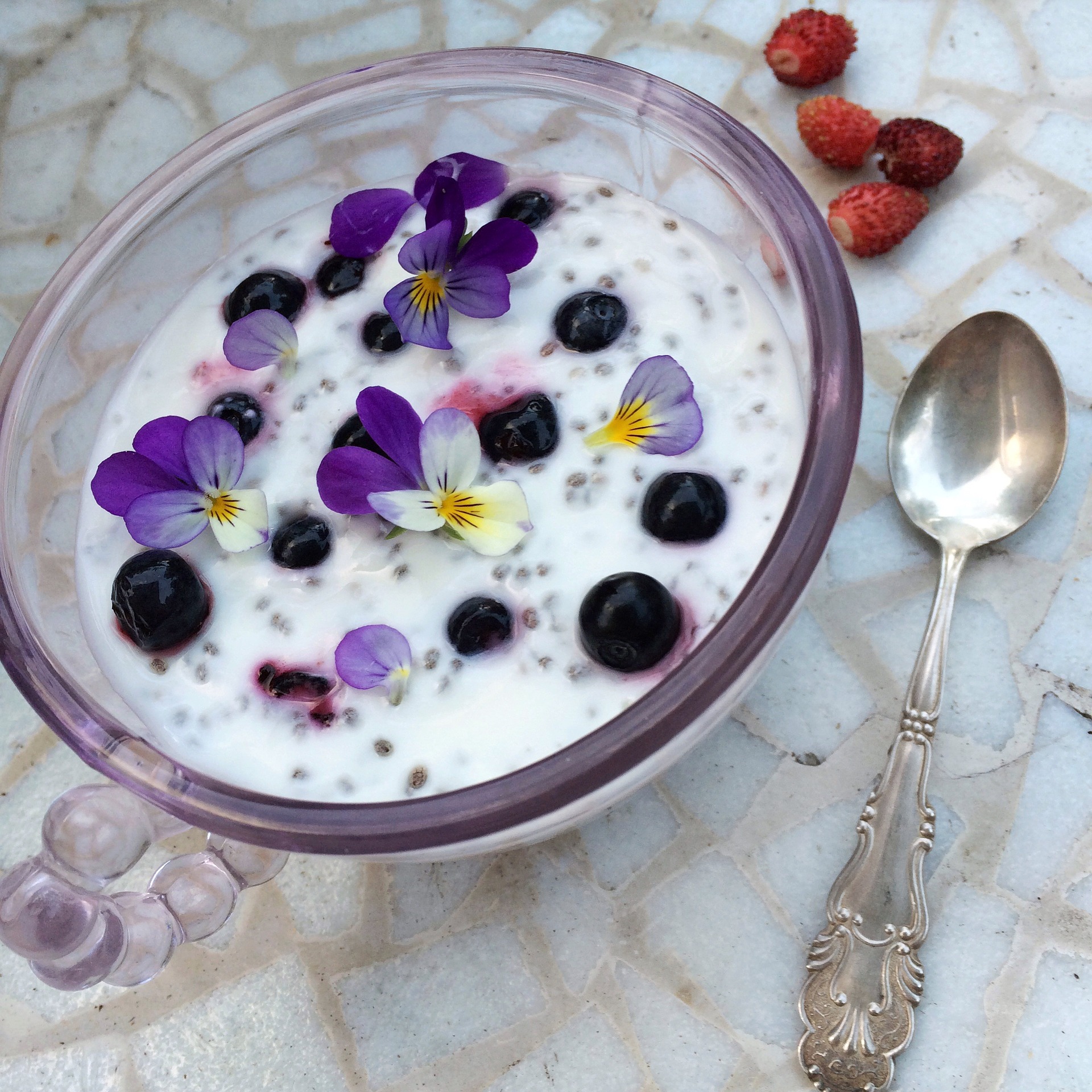 chia seed pudding bowl with berries and violets scattered on top