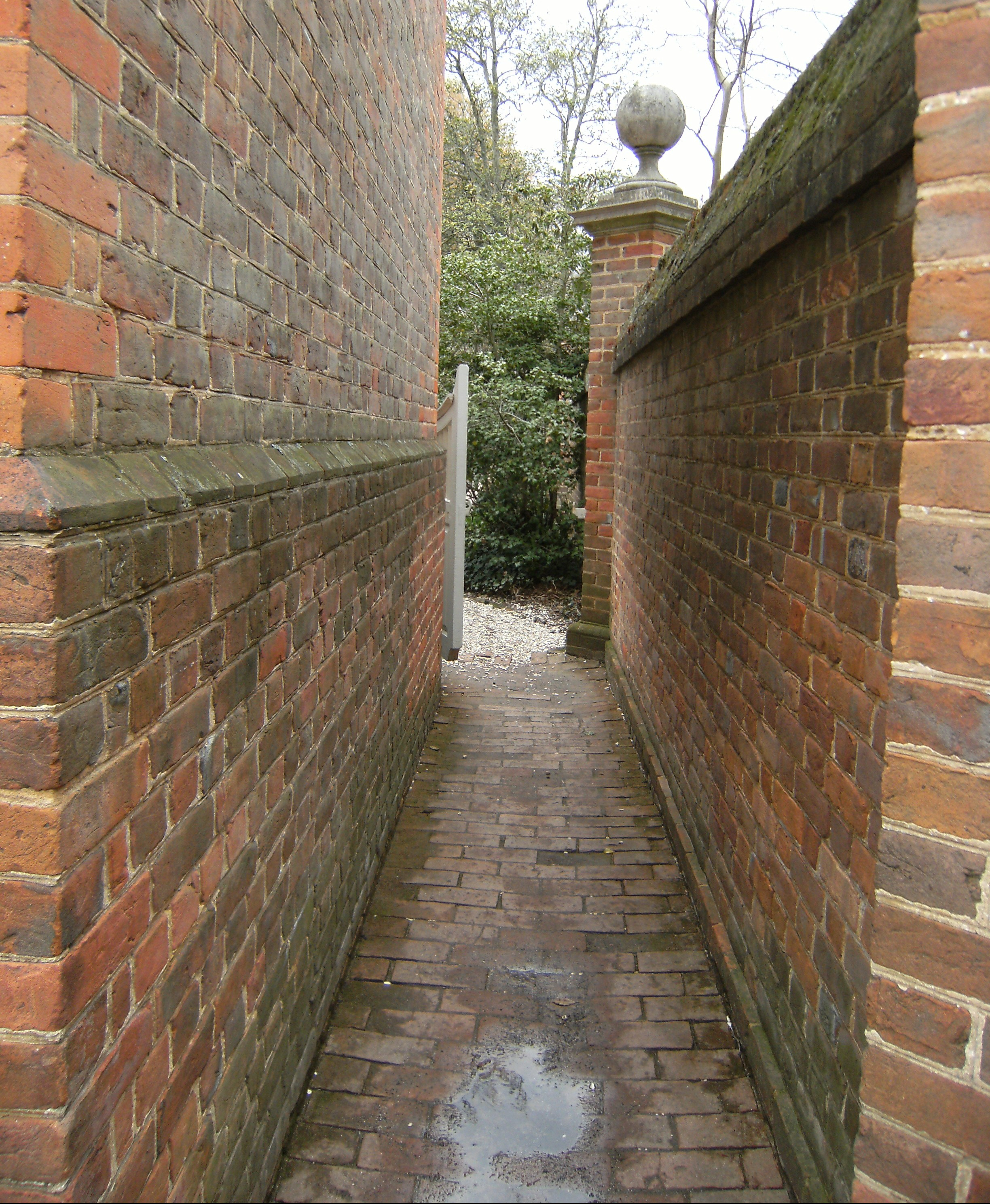 A brick wall stretches to the garden gate