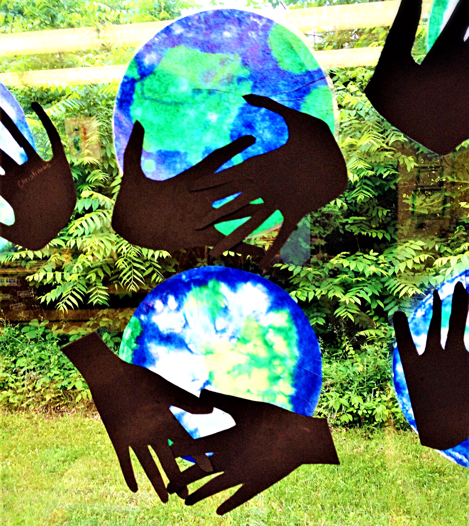 paper cutout hands hold a circle colored blue and green to resemble the Earth