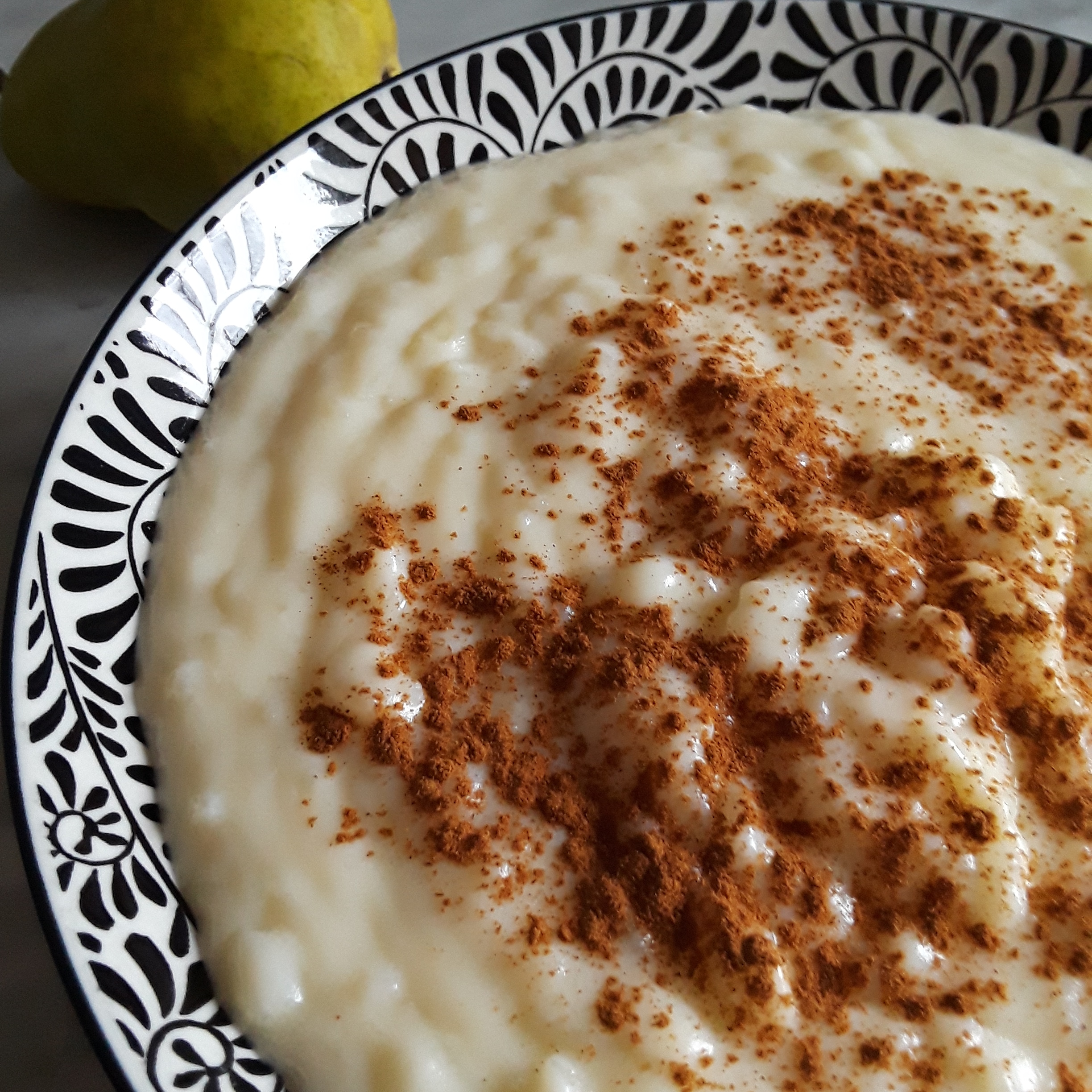rice pudding in a large serving bowl is sprinkled with cinnamon