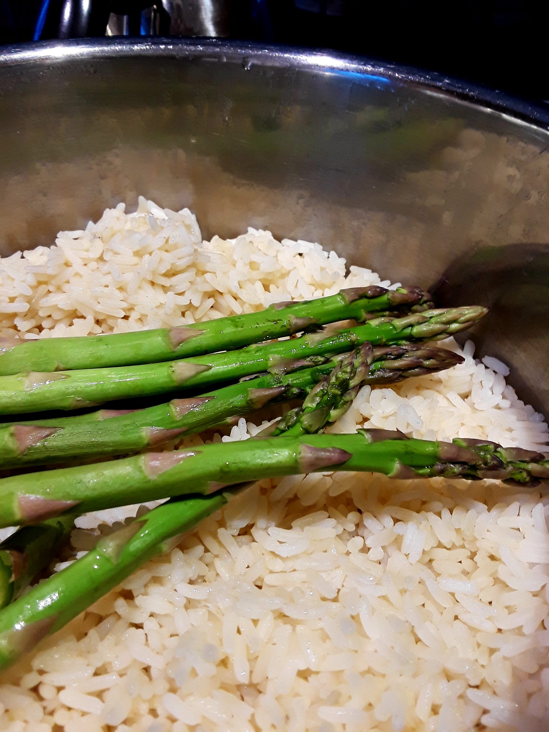 asparagus spears are spread out on top of cooked rice in the rice pot