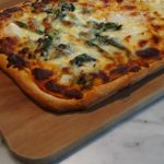 Baked homemade pizza with spinach and cheese toppings